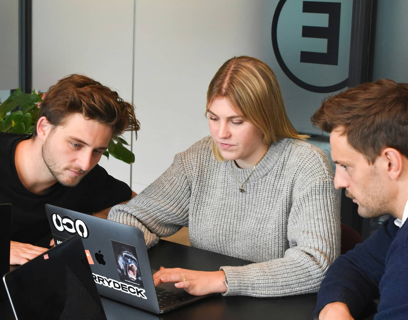 Three people sitting around a laptop