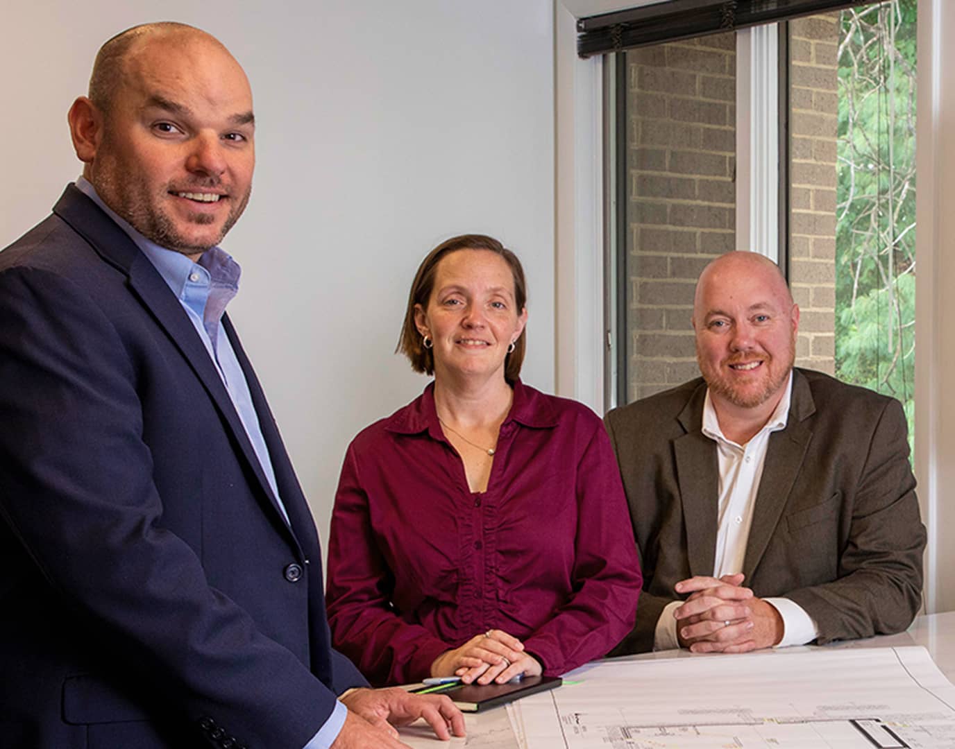 Three Arium employees smiling at the camera in an office room