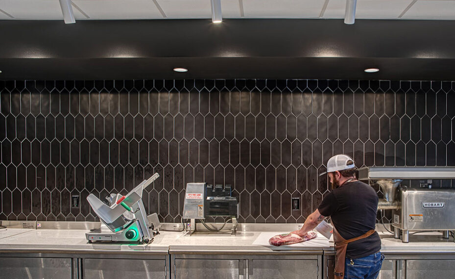 Butchers Club interior of man slicing meat at counter
