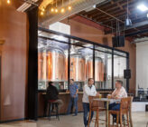 Checkerspot Brewery interior of people talking at tables and view of brewery production area