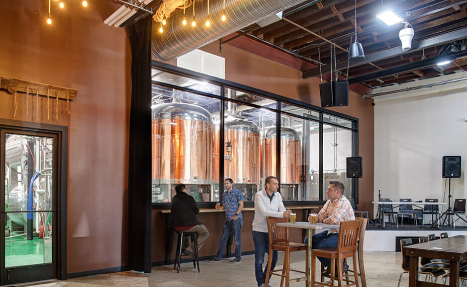 Checkerspot Brewery interior of people talking at tables and view of brewery production area